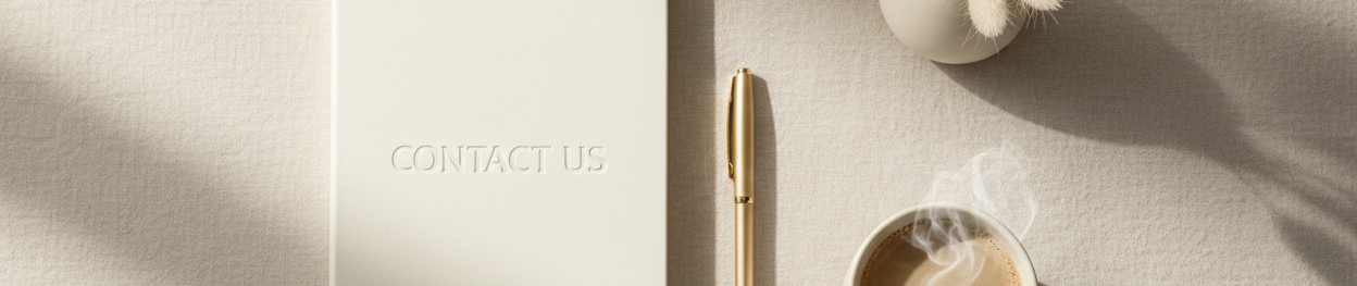 Notebook with 'Contact Us' text, pen, and coffee cup on a light surface